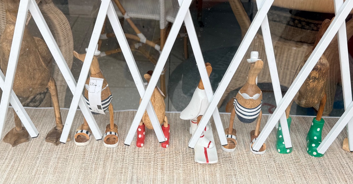A set of carved birds with clothing behind a window fence at the Indonesian export store.